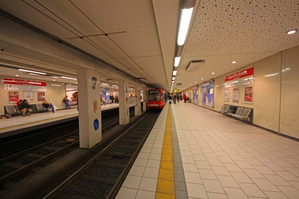 Die Haltestelle Appellhofplatz, auf den Säulen in der Mitte: Die Kölner Köpfe, Bild: ReferenceBK, CC BY-SA 3.0 via Wikimedia Commons